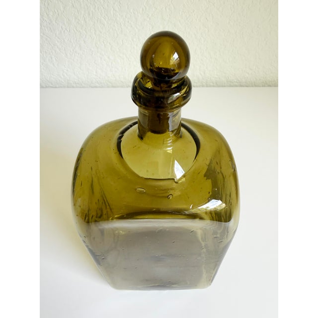 A unique olive green, blown glass decanter with original stopper, circa 1950's, likely produced in Italy. The blown glass...