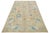 This hand-knotted wool rug has a light brown background and blue frame adorned with multicolor all-over designs. This rug...
