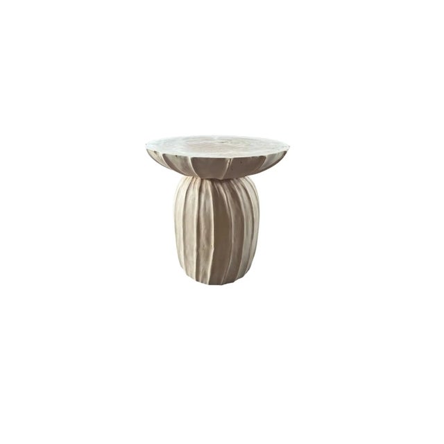 This wonderfully sculptural round side table features a ribbed pattern along its sides. The table's neutral pigment makes...
