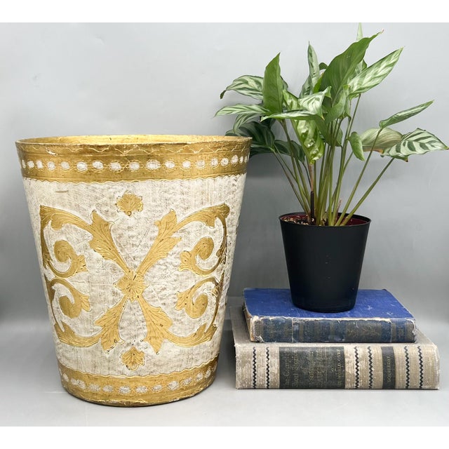 Vintage Italian Florentine-style resin wastebasket featuring an antiqued ivory finish with gilt scrolling acanthus motifs...