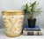 Vintage Italian Florentine-style resin wastebasket featuring an antiqued ivory finish with gilt scrolling acanthus motifs...