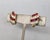Early 1980s goldtone lines of round faux-rubies and clear rhinestones clip earrings. Marked "TRIFARI" on cartouches on the...
