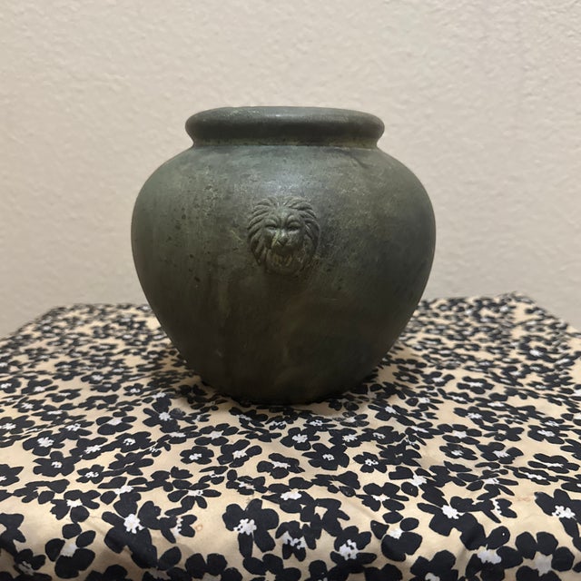The vase showcases a distressed dark green and charcoal bronze patina finish, mimicking the weathered appearance of...