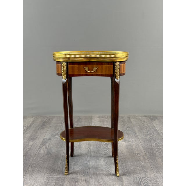 An elegant louis xvi style mahogany side table, featuring a circular top surrounded by an openwork gallery of gilt brass....