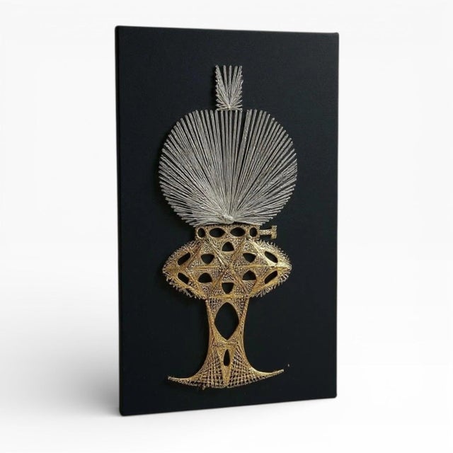 A striking mid-century string art wall piece depicting a stylised oil lamp, executed in metallic gold and silver thread...
