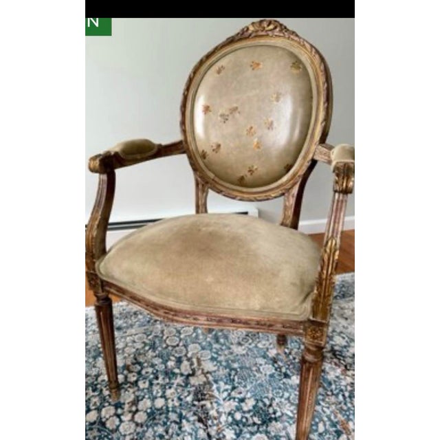 An elegant French Louis XVI style giltwood armchair featuring a classic oval medallion back adorned with hand-painted...