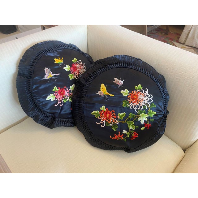 This round pillow features a lustrous black satin fabric, adorned with intricate floral embroidery depicting pink and red...