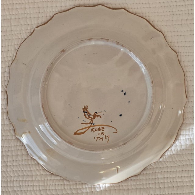 Decorative set of five hand-painted Italian faience plates, each featuring a pastoral landscape scene rendered in warm...