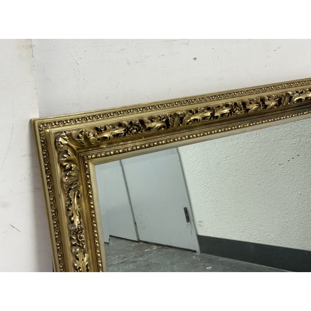 Design Plus Gallery presents a Vintage Ornate Gold Finish Wall Mirror. The mirror frame displays scrollwork and floral...