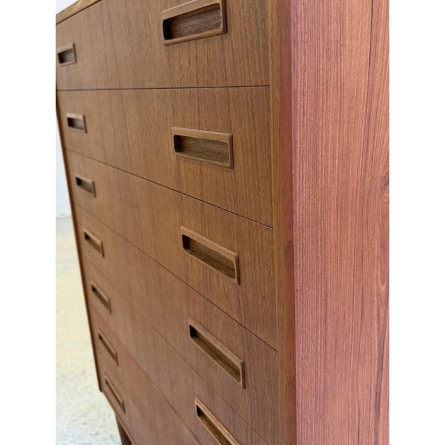 An impressive piece of Danish design for your living space: This tall mid-century teak chest of drawers captivates with...