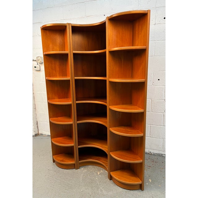 A beautifully crafted vintage Danish modular shelving unit, featuring warm teak construction and distinctive curved...