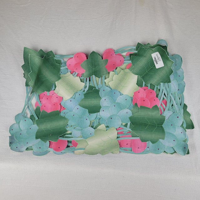 Khazana floral placemat set features a vibrant, multi-colored design with intricately cut-out leaf and berry motifs....