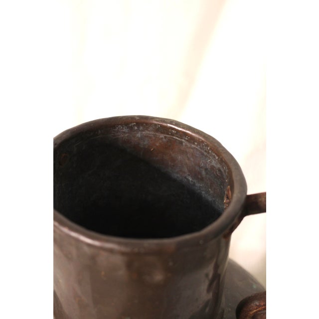A wonderful hammered copper vase or vessel that is very large and unique. 2 cast iron scroll handles on the side of a...