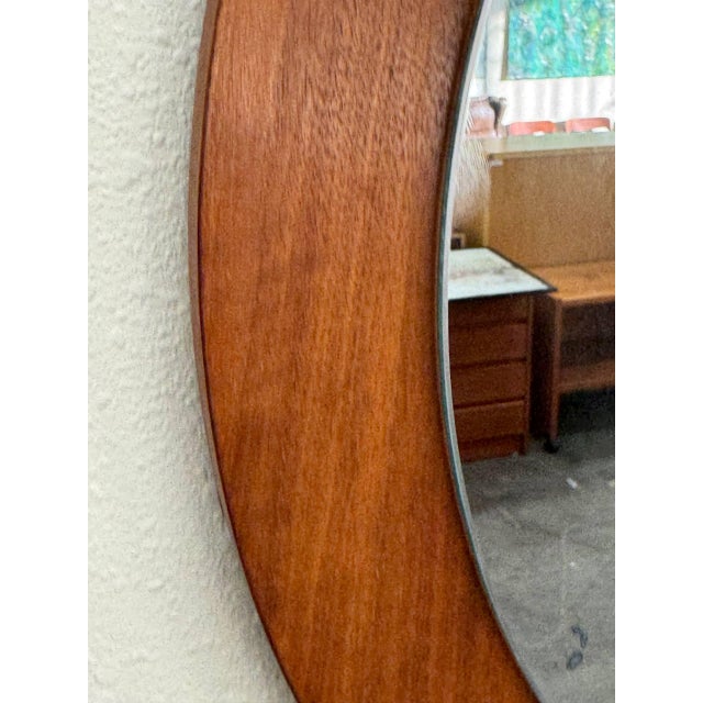 Beautiful mid-century modern round wall mirror crafted in Denmark, featuring a solid teak frame with warm, even grain and...