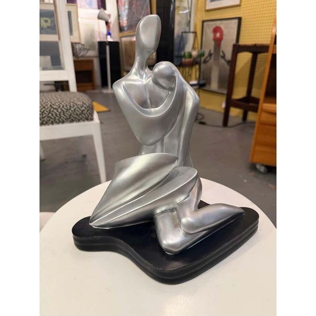 This mid-century modern plaster sculpture, finished in silver, depicts two abstracted figures in an intimate embrace. The...