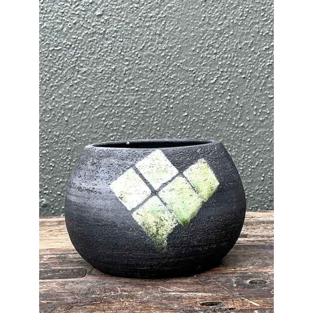 This striking vintage studio pottery bowl exemplifies the allure of the Raku firing process, an ancient Japanese technique...