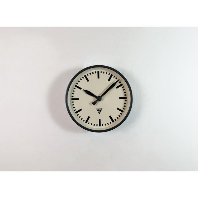 This wall clock was produced by Pragotron in former Czechoslovakia during the 1960s. It features a dark grey metal frame,...