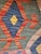 A striking vintage Afghan kilim, handcrafted in wool, featuring a rich tribal geometric design and a sophisticated color...