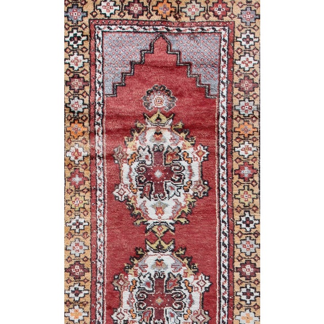 This vintage Turkish runner, hand-knotted from high-quality wool, features a warm color palette that includes faded soft...