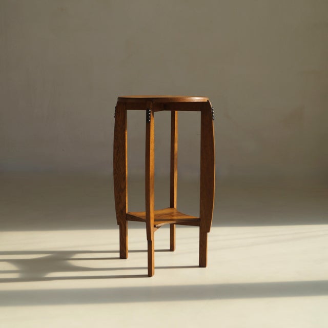 An Amsterdam School pedestal table with an elegant design, in soild oak and black stained ''pearl'' woodcarved details at...