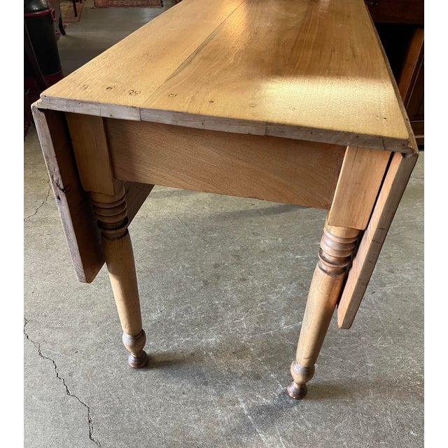 Antique drop leaf table with turned legs. Appears to be walnut with a fairly uniform fading/bleaching, making for an...