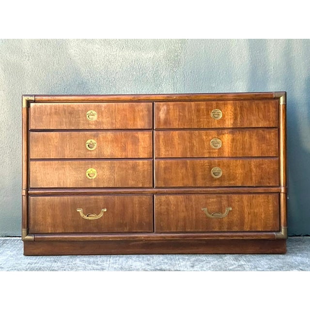 This vintage Drexel campaign dresser is a striking example of mid-20th-century case goods, distinguished by its warm,...