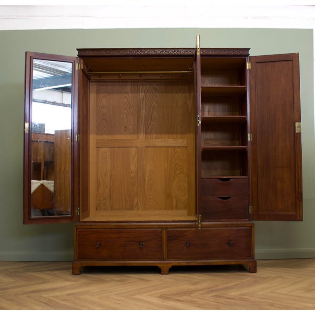 A quality Georgian Revival mahogany triple wardrobe by the renowned British makers Maple & Co., dating from the early 20th...