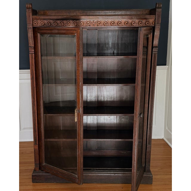 Carved oak vitrine from the turn of the twentieth century, bridging late Victorian ornament and the discipline of the Arts...