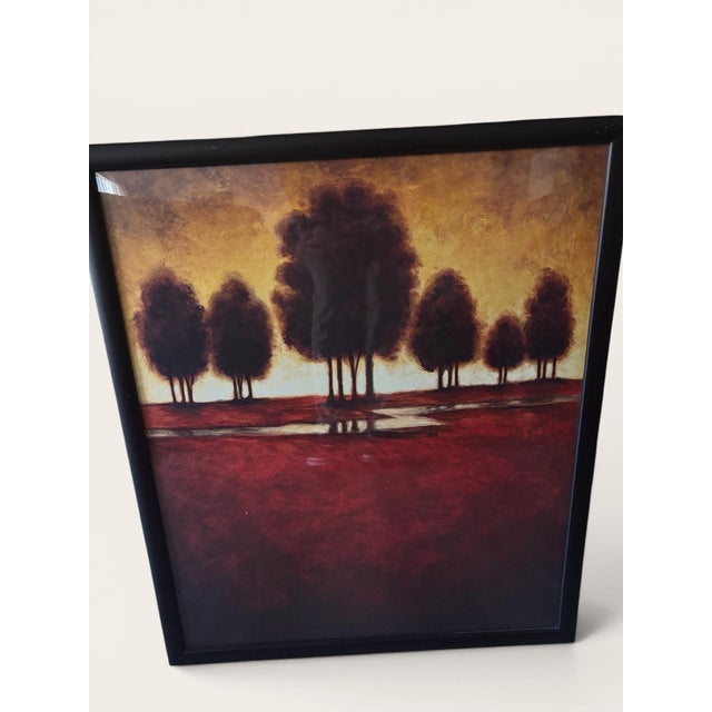 This framed art print features a beautiful scene of a red field with silhouetted trees against a warm orange sky. The...