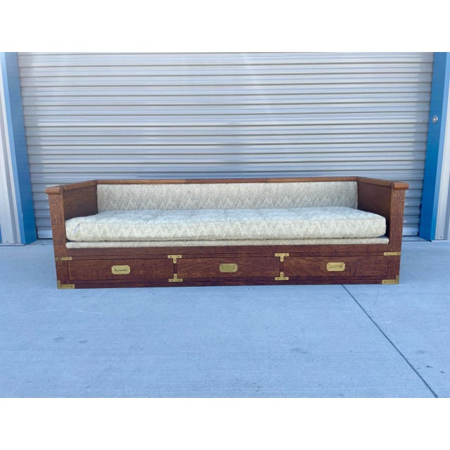 This monumental mid-century Campaign-style daybed sofa by Marge Carson showcases the dramatic, highly figured wood...