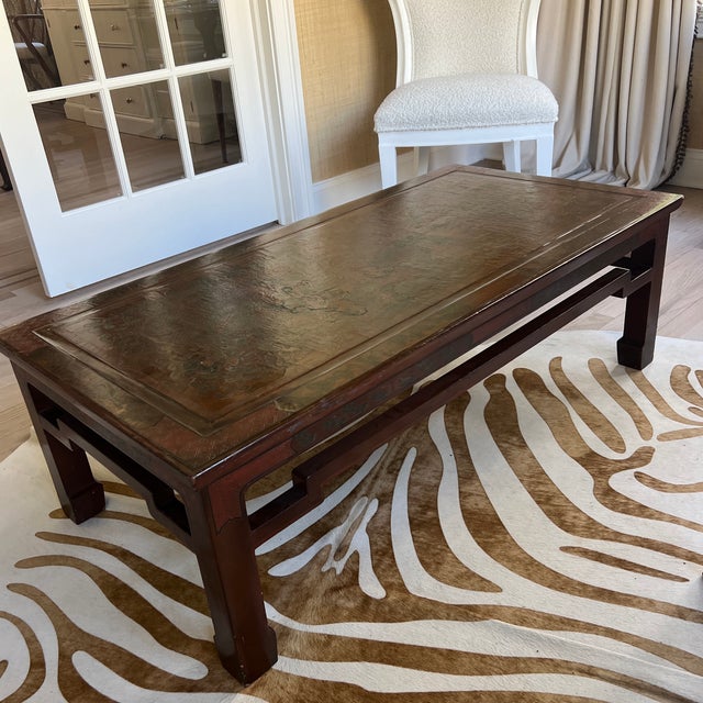 A vintage Chinese black and red lacquer etched coffee table. The rectangular dark table features a top etched with...
