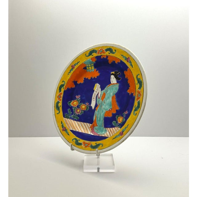 A bold blue and yellow decorative porcelain charger plate, hand-crafted in Japan around the 1920s. Hand-painted with a...