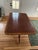 Classic wood dining table. Has a dark wood top with lighter wood inlay border. Features two pedestal bases with brass...