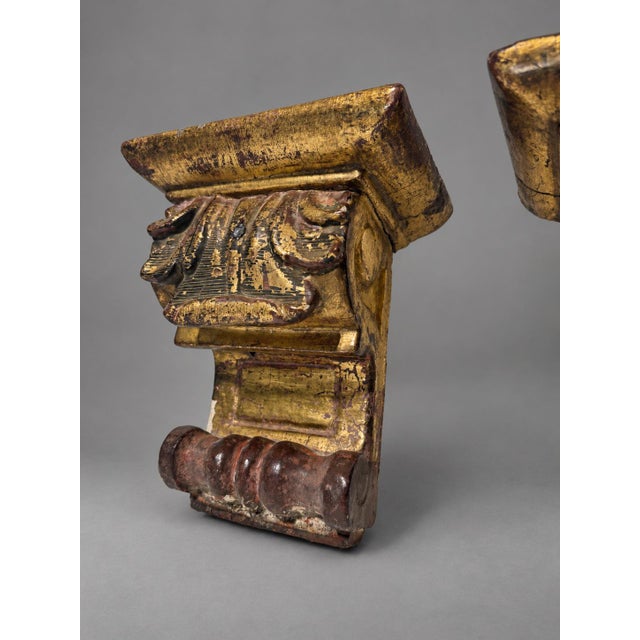 A pair of European carved wooden wall brackets with gilded and painted decoration, nineteenth century. Each takes the form...