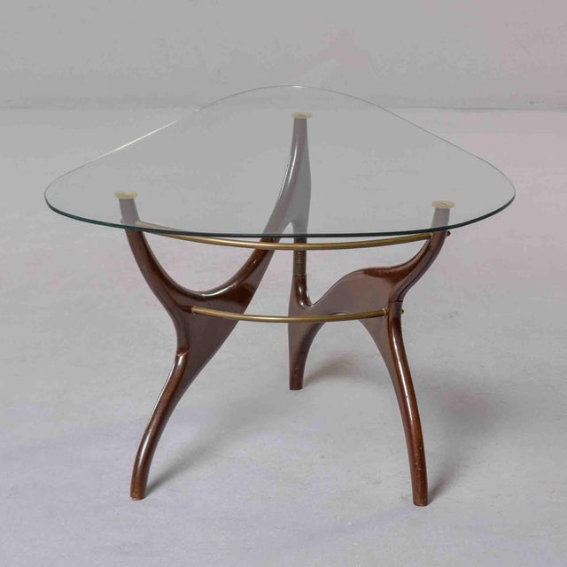 This Italian cocktail table is built around a sculptural base of lacquered walnut, composed of three swept legs that...