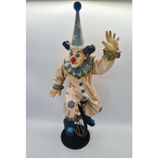 A striking, large decorative figure depicting a circus clown riding a unicycle, created by jun asilo. The sculpture is...