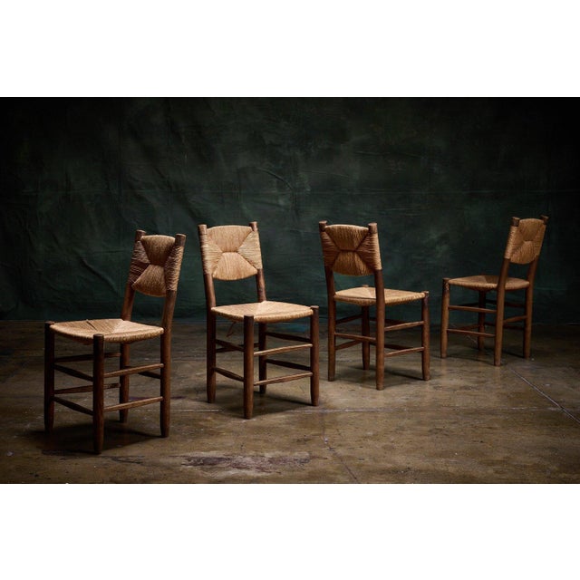 Charlotte Perriand set of four straight back chairs from the 1960s featuring woven seats and backs with a distinctive...