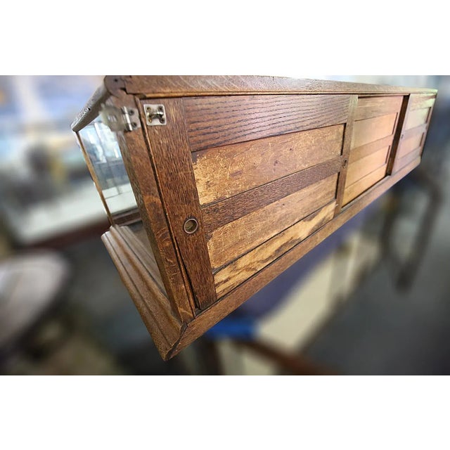 Early 20th century oak and glass showcase with mirrored sliding back doors.