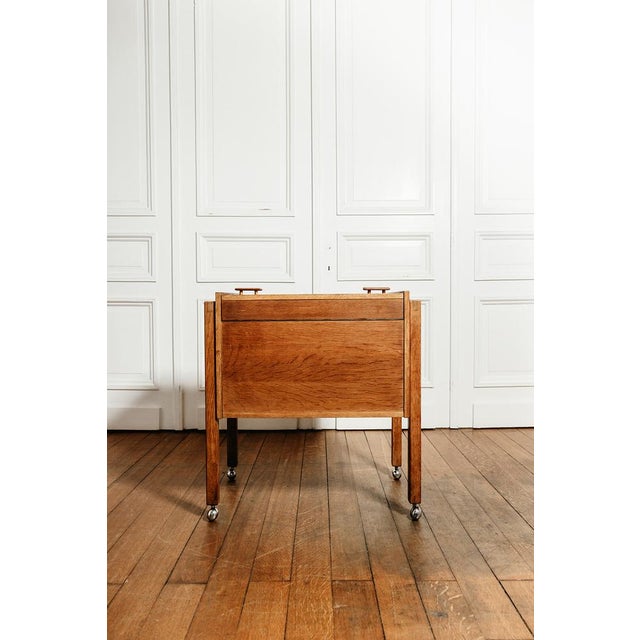 Vintage bar cabinet on casters. Its two upper doors open to reveal a storage compartment with two serving shelves topped...