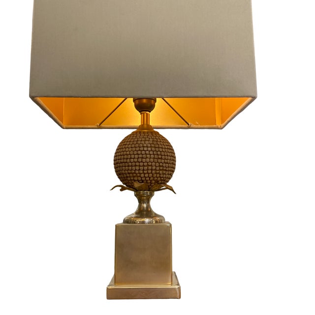 A small lamp made of gilded brass, following the design of Maison Jansen. The lamp body features a pineapple at its...