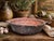 A beautifully aged vintage copper-tone serving pan featuring sculptural brass-toned side handles and a richly weathered...