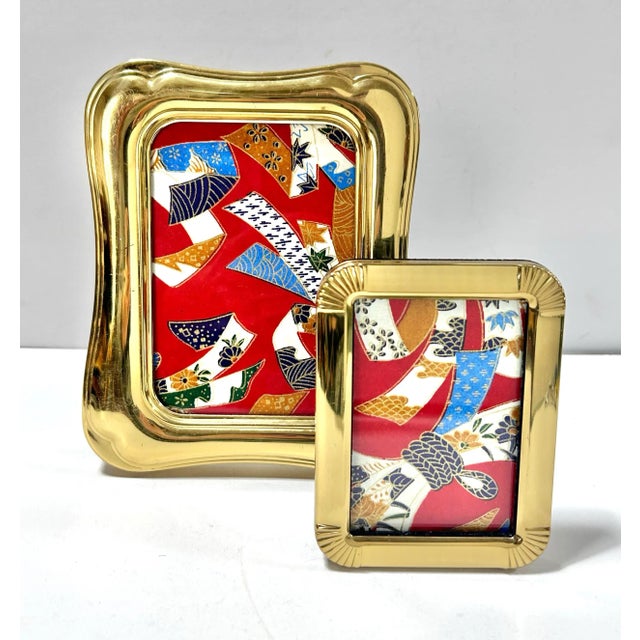 A coordinating pair of vintage brass tabletop picture frames in two complementary designs. The larger frame has a softly...