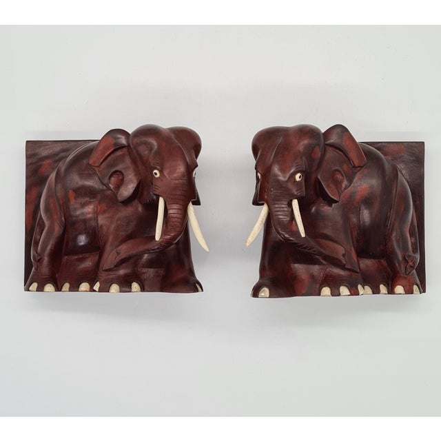 A pair of decorative bookends in the form of carved elephants. Made of solid wood with a dark, warm color. Details –...