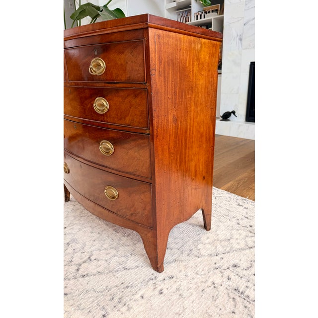An exceptional vintage Danish bow front chest of drawers, masterfully crafted in richly figured mahogany and distinguished...
