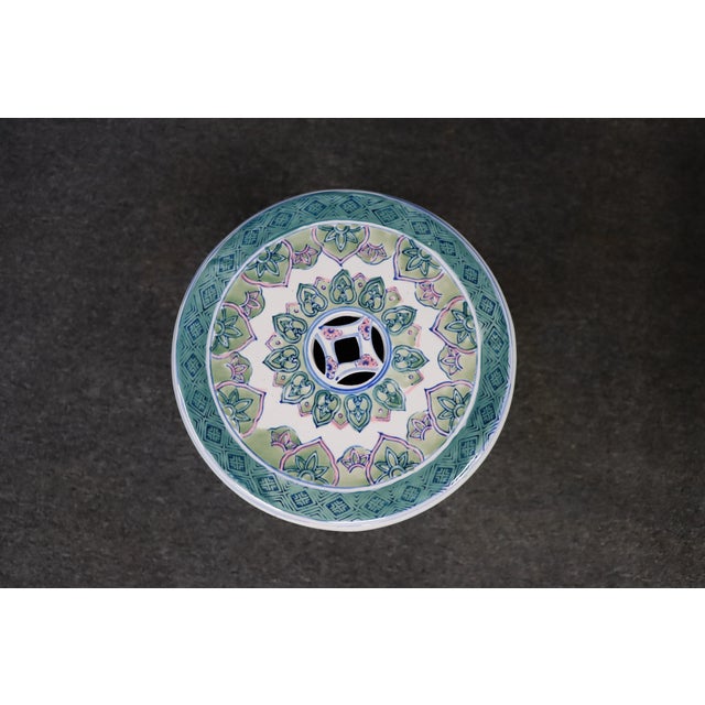 Chinese porcelain garden stool with fitted lid, decorated in a palette of blue, green, and pink with stylized...