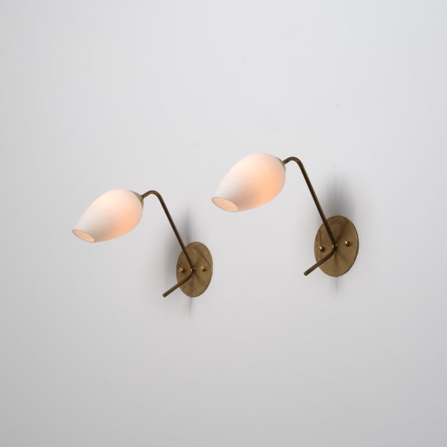 Elegant pair of Italian wall sconces manufactured in the 1950s, featuring slender angular brass arms supporting tapered...