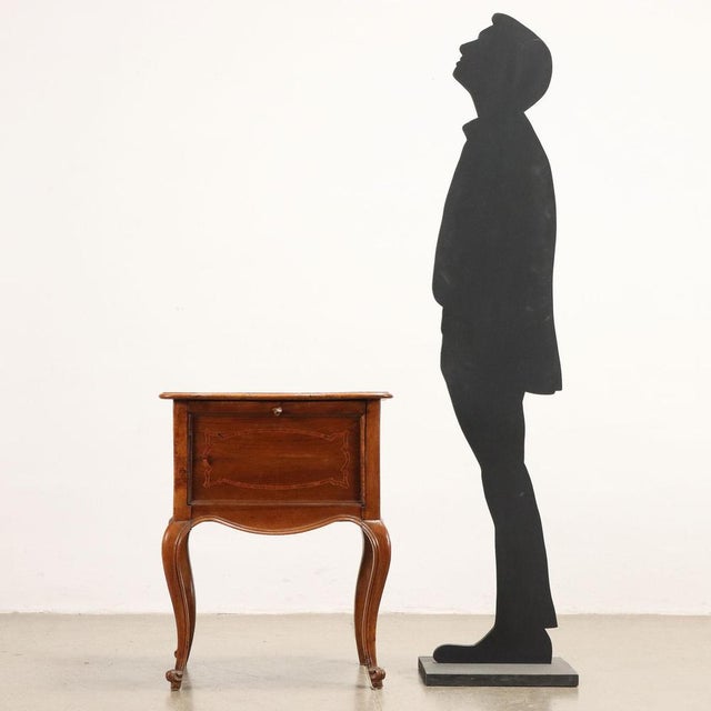 Open bedside table in walnut with shaped and inlaid top, front with door bearing carved knob and wavy legs with carved...