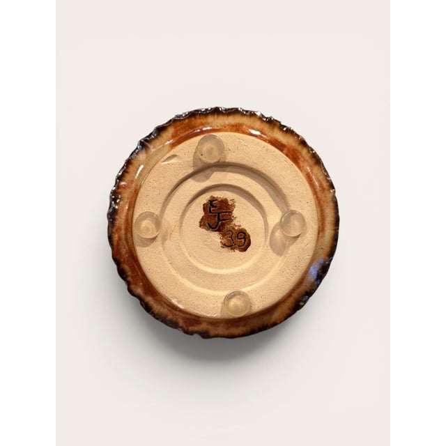 A glazed ceramic vase by Gene Farkus, designed with a rounded bottle-form body, narrow neck, and footed base. The piece...