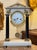 French mantel clock in the Empire style, featuring a white marble case with black column supports and classical gilt...