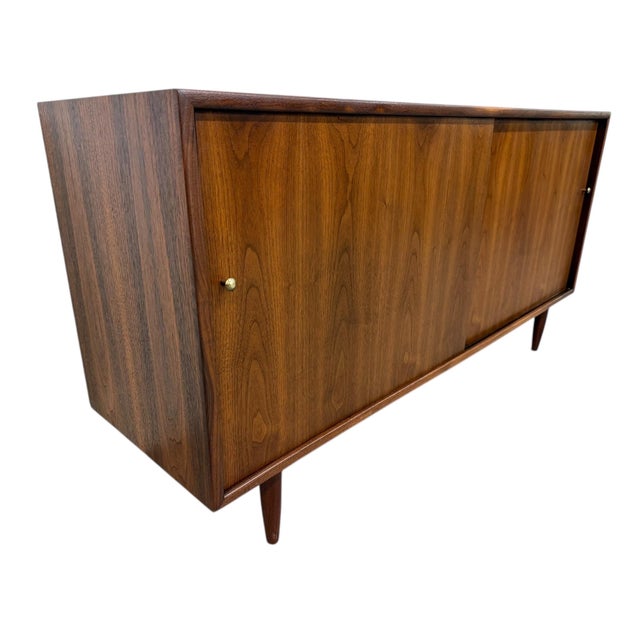 Elevate your space with this stunning 1960s American-made walnut sliding door cabinet, a true Mid-Century Modern classic....